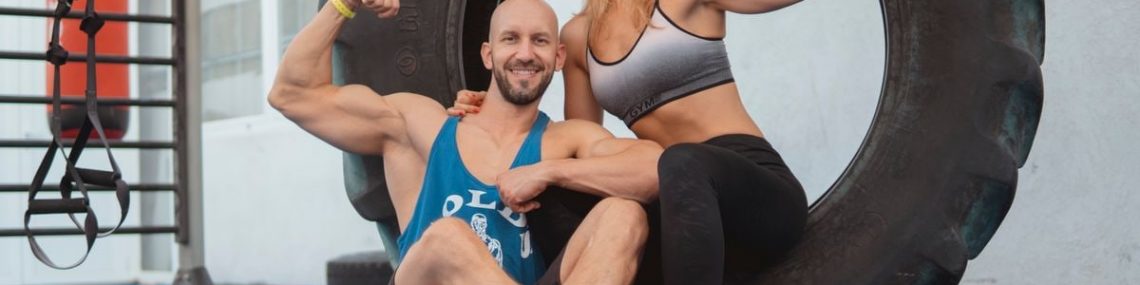 Energetic couple showing strength and fitness at the gym with a large tire.